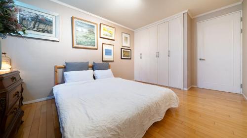 a bedroom with a white bed and a wooden floor at Museum Stay in Yongin