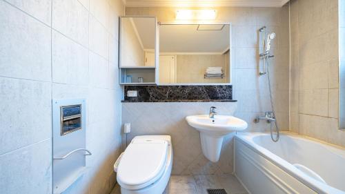 a bathroom with a toilet and a sink and a tub at Museum Stay in Yongin