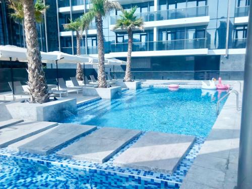 ein Pool mit Palmen und ein Gebäude in der Unterkunft Super Elegant studio apartment-Sparkle tower By SWEET HOMES in Dubai