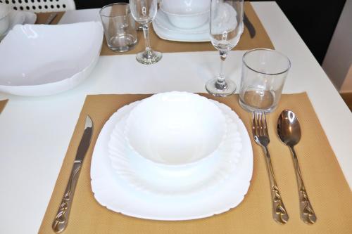 un plato blanco en una mesa con vasos y cubiertos en ZAPBED House - Luxury Holiday Homes in Yas Island en Abu Dabi