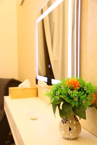 a vase of flowers on a table with a television at ZAPBED House - Luxury Holiday Homes in Yas Island in Abu Dhabi