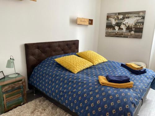1 cama con edredón azul y almohadas amarillas en Le Loft Vintage Epernay avec Netflix, Vélos, Parking gratuit en Épernay