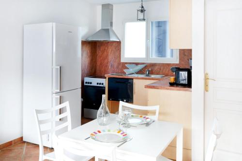 une cuisine blanche avec une table et des chaises blanches dans l'établissement Appartement au pays basque, à Ahetze