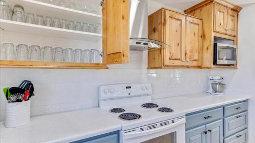 a white kitchen with a stove and wooden cabinets at Play & Gather in Luxury,Pets too! Close to it Everything! in Orem