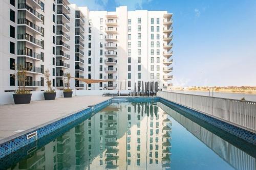 a swimming pool in front of some apartment buildings at ZAPBED House - Luxury Holiday Homes in Yas Island in Abu Dhabi