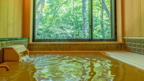 a pool of water in a room with a window at Shionoyu Onsen Rengetsu in Nasushiobara