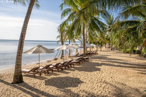 een rij stoelen en parasols op een strand bij Sea Sense Resort in Phu Quoc