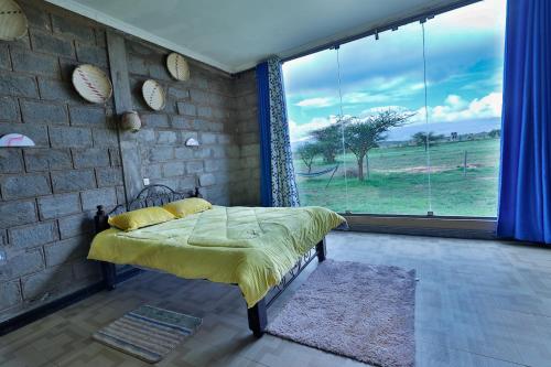 a bedroom with a bed and a large window at Amboseli Cultural Camping in Amboseli