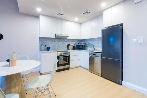 a kitchen with white cabinets and a black refrigerator at Burj Al Arab View - 1BR in MJL Lamtara 1- Burj Al Arab View 703 in Dubai