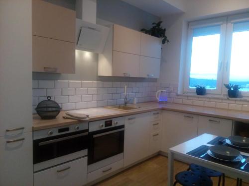 a kitchen with white cabinets and a stove top oven at Leśny Loft in Gdynia