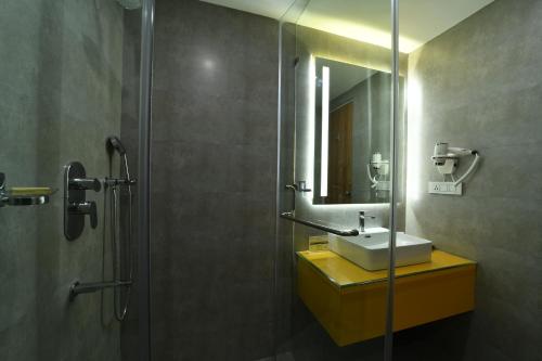 a bathroom with a sink and a shower with a mirror at The President Hotel, kumarapark in Bangalore