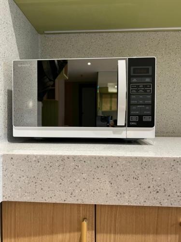 a microwave oven sitting on top of a counter at Podomoro City Deli Medan Tower Empire - Japandi Style - 2BR Family Suite 3 beds - 87m in Medan