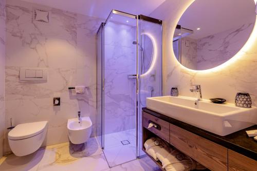 a bathroom with a sink and a toilet and a shower at Hotel Welponer in Selva di Val Gardena