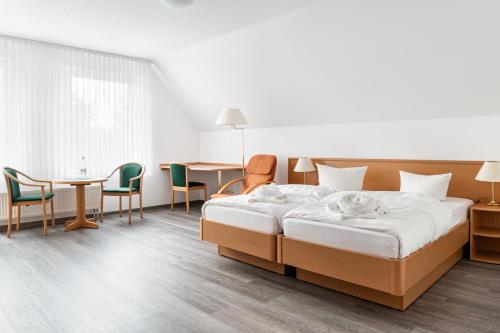 um quarto de hotel com uma cama, uma mesa e cadeiras em Löwen Pension em Unterlüß