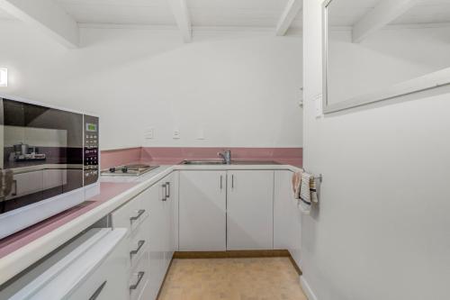 a white kitchen with a sink and a microwave at Capital Lodge Motor Inn in Wellington
