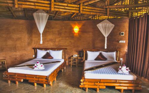 two beds in a room with two bedsitures at Hanchey Bamboo Resort in Kampong Cham