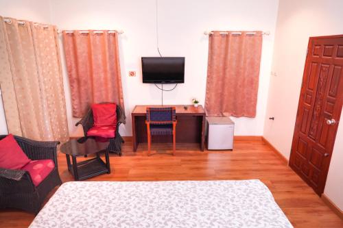 a room with a bed and a desk and a television at Guesthouse Phuket Airport in Ban Bo Han