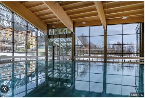 einen Innenpool in einem Gebäude mit Glasfenstern in der Unterkunft Chalet Dachstein in Ramsau am Dachstein