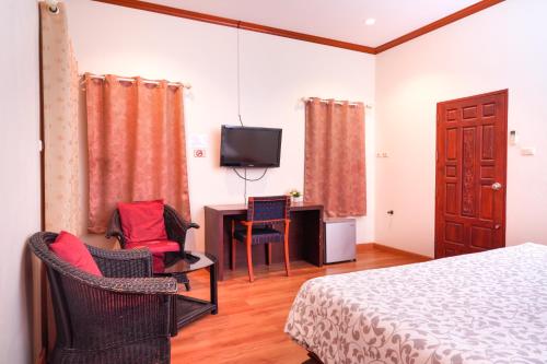 a bedroom with a bed and a desk and a tv at Guesthouse Phuket Airport in Ban Bo Han