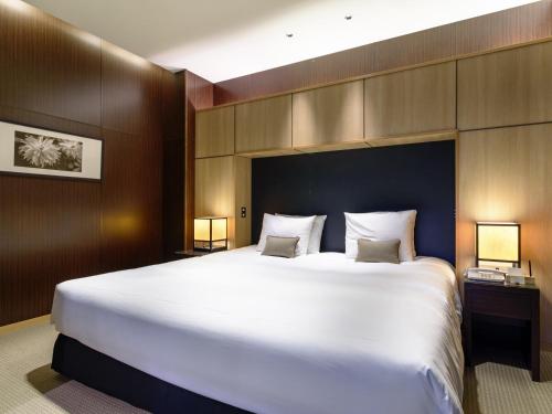 a large white bed in a room with two lamps at Fufu Atami in Atami