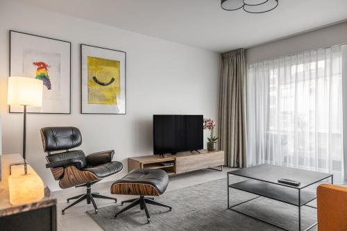 a living room with a flat screen tv and a chair at Casselbergh Residences Petunia - De Haan in De Haan