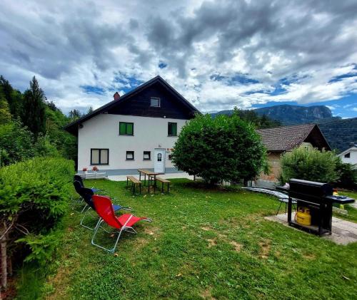a house with a yard with two chairs and a grill at Dolar Rooms in Bled