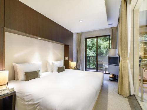 a bedroom with a large white bed and a large window at Fufu Atami in Atami