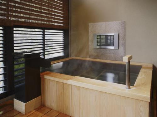 a hot tub in a room with a window at Fufu Atami in Atami