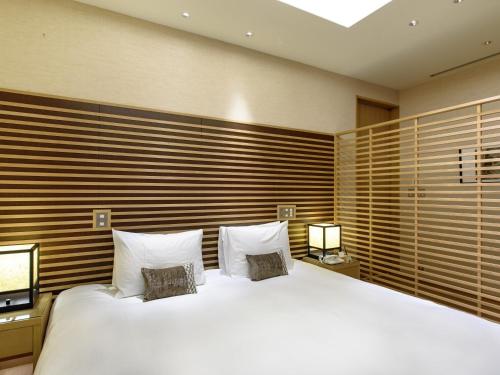 a bedroom with a large white bed with two pillows at Fufu Atami in Atami