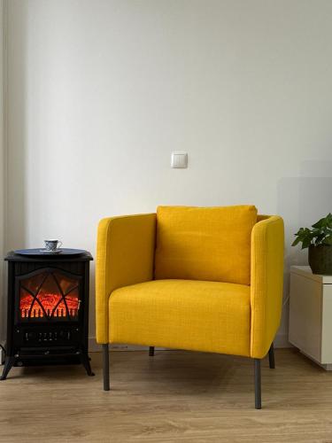 a yellow chair in a living room with a fire place at The apartment near the beach in Oeiras in Paço de Arcos