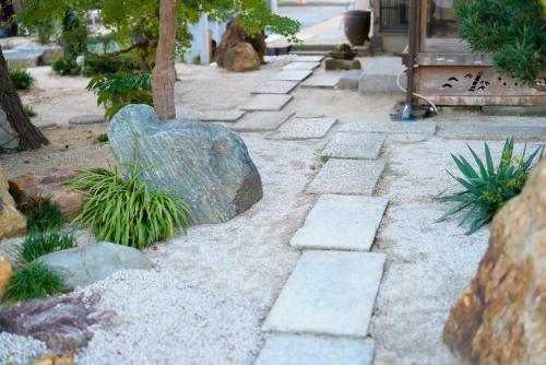 a stone pathway with a large rock and plants at Itako Shimagen -潮来の古民家 島源- in Itako