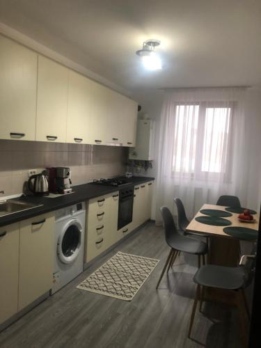 cocina con mesa y lavadora en Ilinca-ZGATIA, en Piatra Neamţ