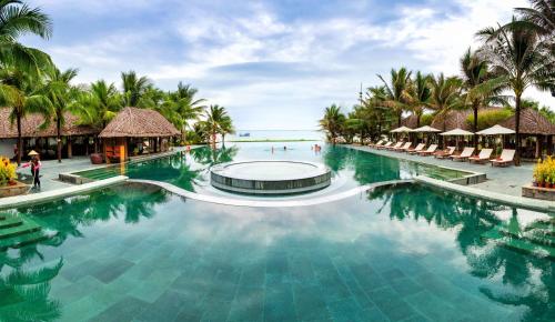 a swimming pool at a resort with palm trees at Sonata Resort & Spa in Phan Thiet