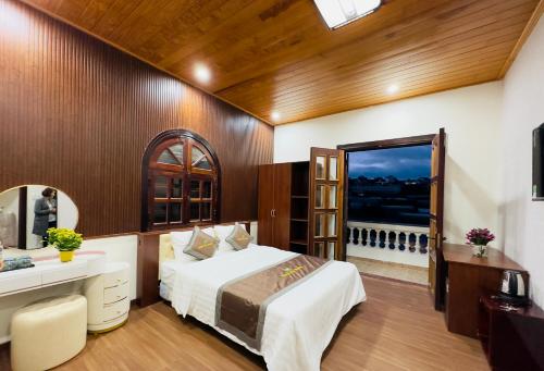 a bedroom with a bed and a desk and a window at Dalat Eco House in Trai Mat