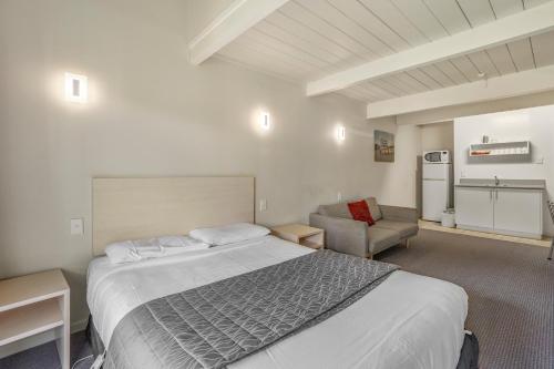 a bedroom with a large bed and a chair at Capital Lodge Motor Inn in Wellington