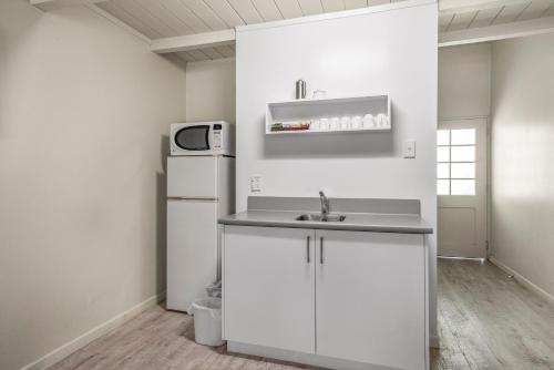 a white kitchen with a sink and a refrigerator at Capital Lodge Motor Inn in Wellington