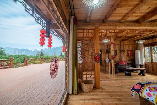 a wooden cabin with a deck with a view of the mountains at Forest Glass inn in Zhangjiajie