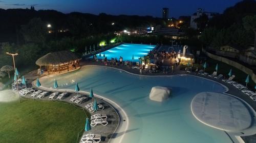 a large swimming pool at night with tables and chairs at Estivo Premium Deluxe mobile homes on Camping Malibu Beach in Lido di Jesolo