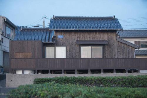 a house with a wooden facade with a roof at Jikukan Mukae in Taisha