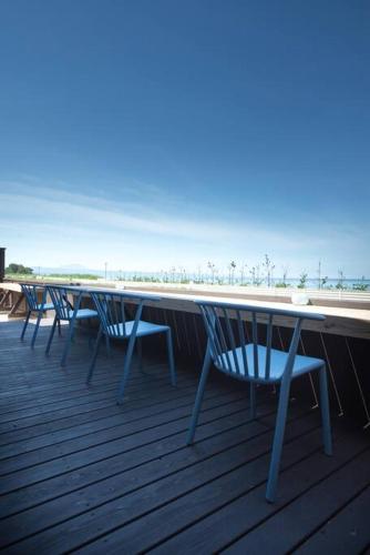 a row of tables and chairs on a deck with the beach at Jikukan Mukae in Taisha