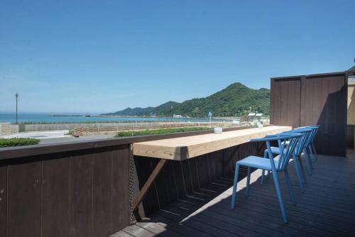 a wooden table and chairs on a deck with the beach at Jikukan Mukae in Taisha