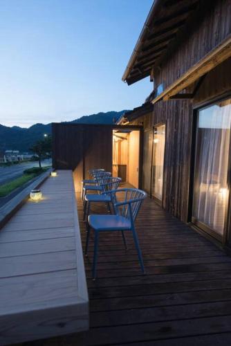 a row of chairs sitting on a wooden deck at Jikukan Mukae in Taisha