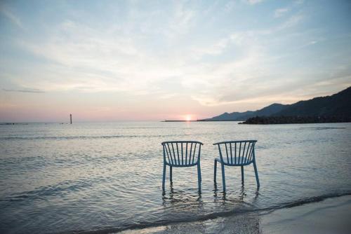 two chairs sitting in the water on the beach at Jikukan Mukae in Taisha