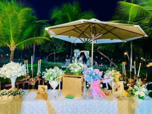 a table with an umbrella and flowers on a beach at Sonata Resort & Spa in Phan Thiet