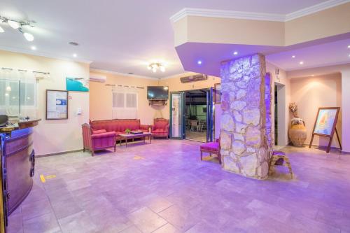 a living room with pink furniture and a stone pillar at Vergina Star Hotel in Nikiana