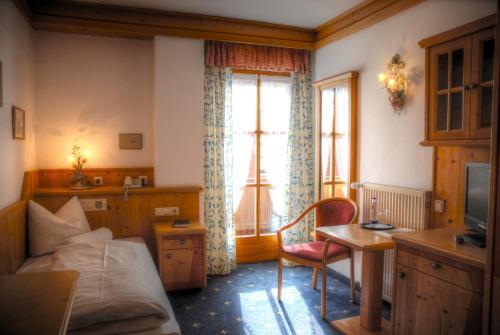 a bedroom with a bed and a desk and a window at Hotel Hölzer Bräu by Lehmann Hotels in Ebersberg
