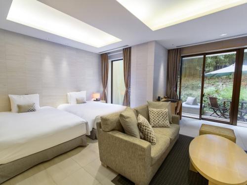 a hotel room with two beds and a couch and a table at Fufu Atami in Atami