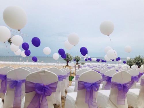a bunch of white chairs and balloons on a beach at Sonata Resort & Spa in Phan Thiet