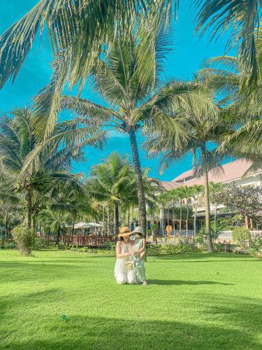 a bride and groom standing under a palm tree at Sonata Resort & Spa in Phan Thiet