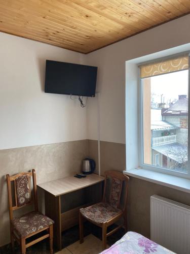 a room with a desk and two chairs and a television at Домашній Затишок in Stryi